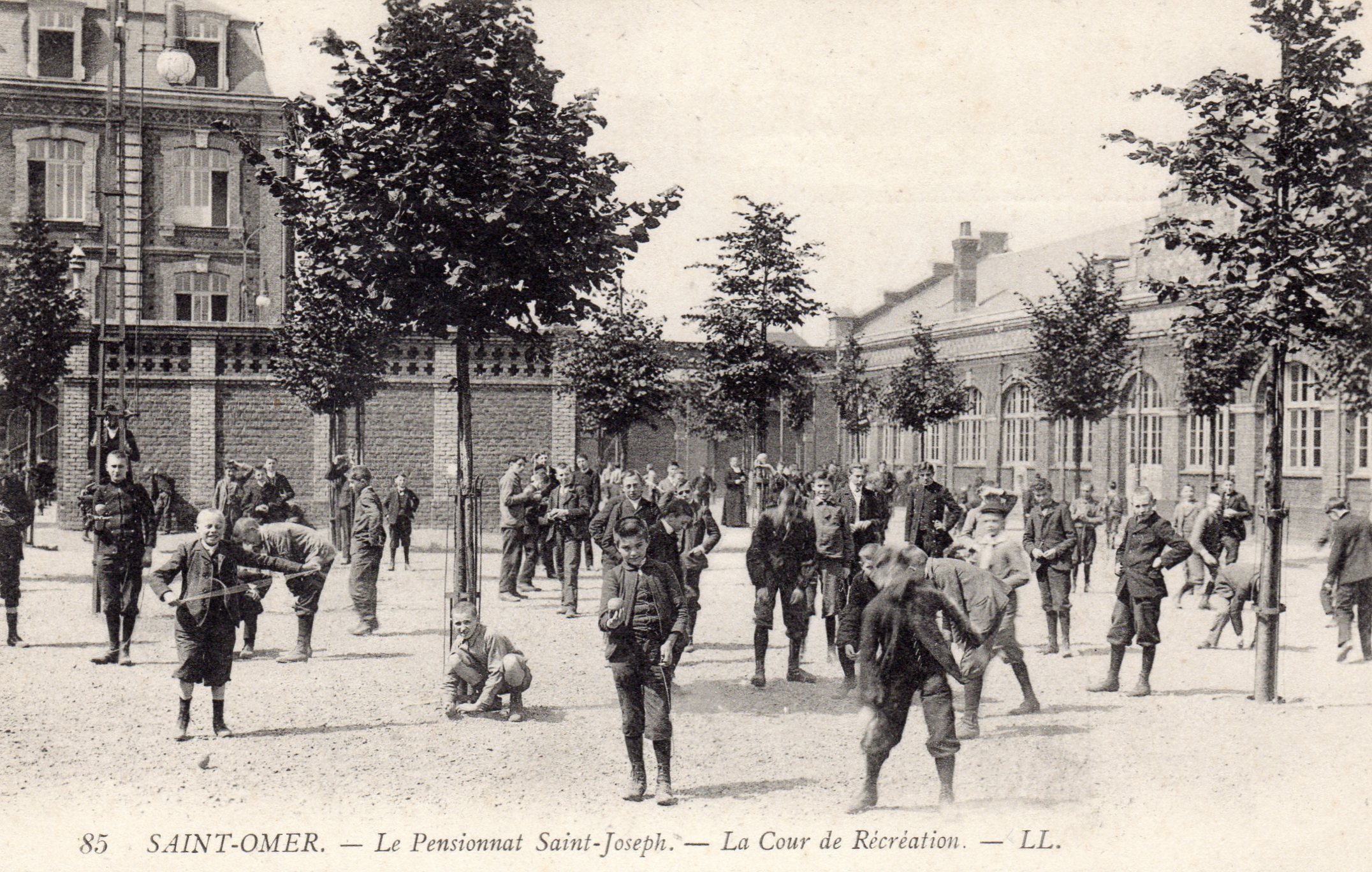 La cour de récréation du pensionnat avec de nombreux arbres, pas encore assez grands pour faire de l'ombre. 